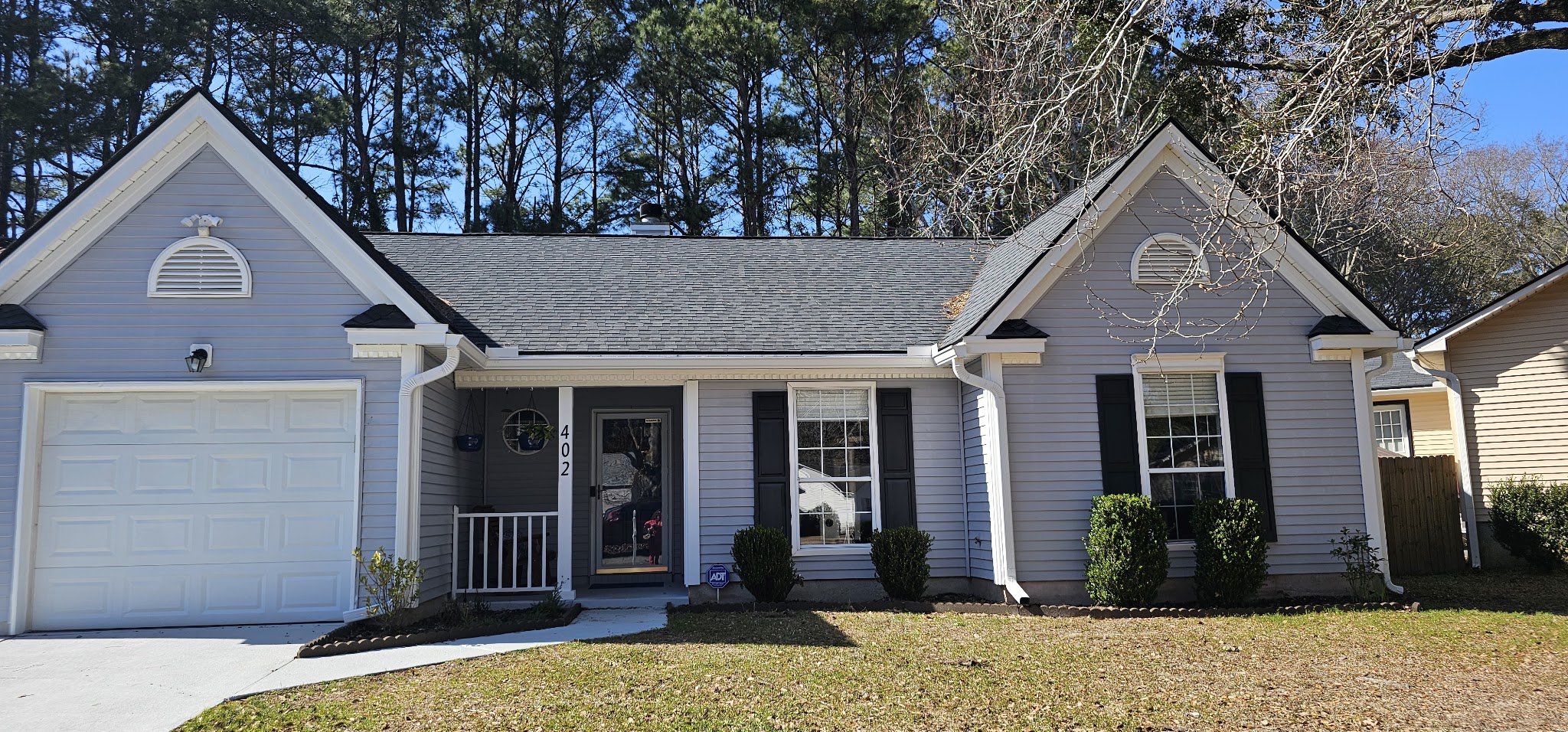 Single-story lilac home with a white garage door and fresh gutters