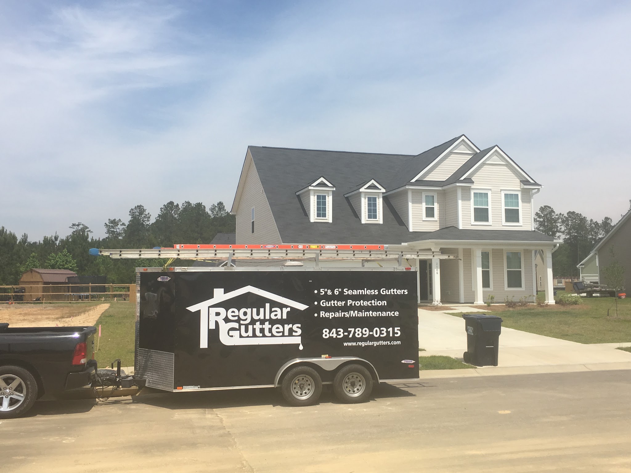 Our Regular Gutters trailer and truck parked outside a finished home