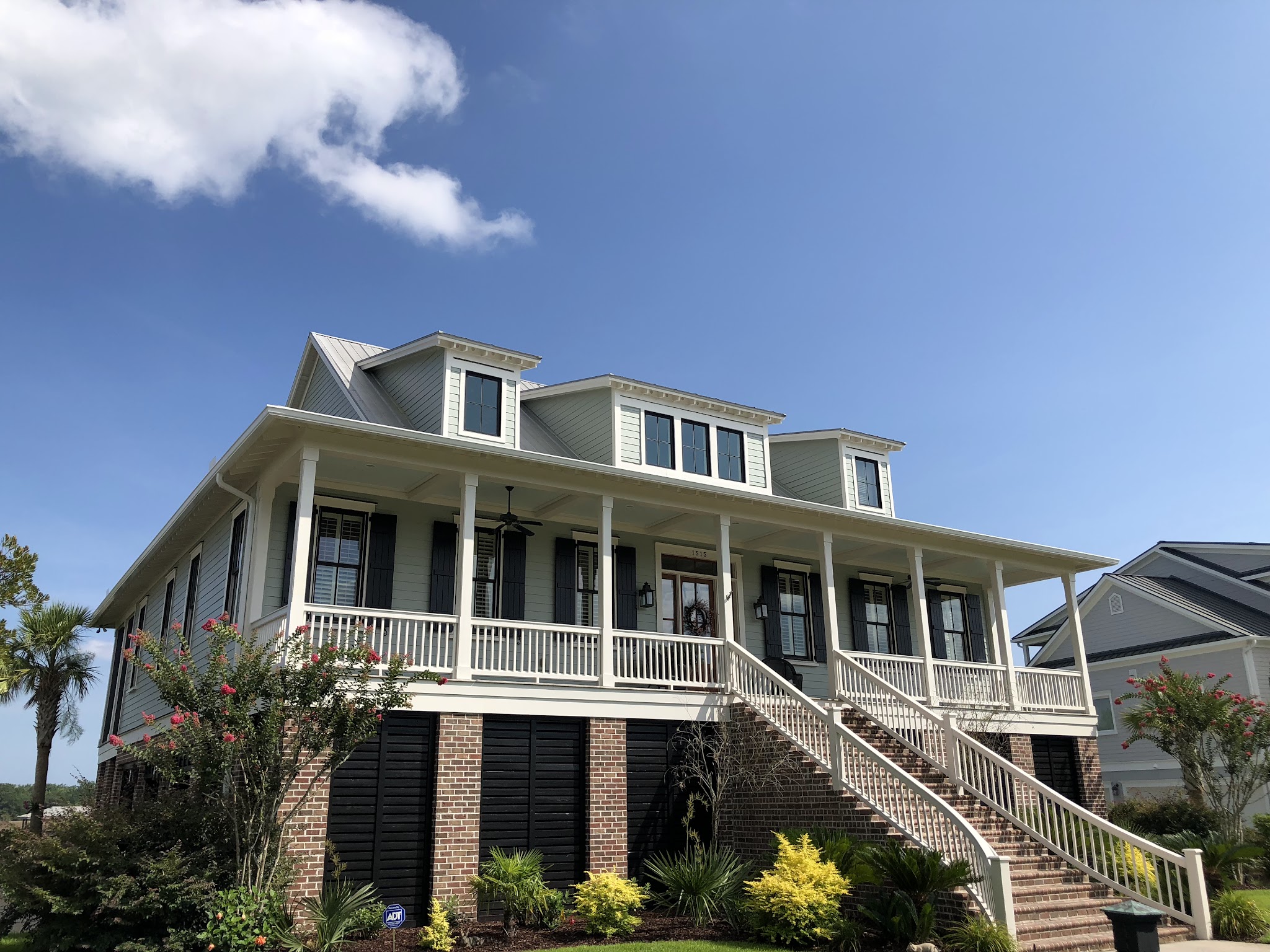 Large Lowcountry home with a wraparound porch and clean white gutters