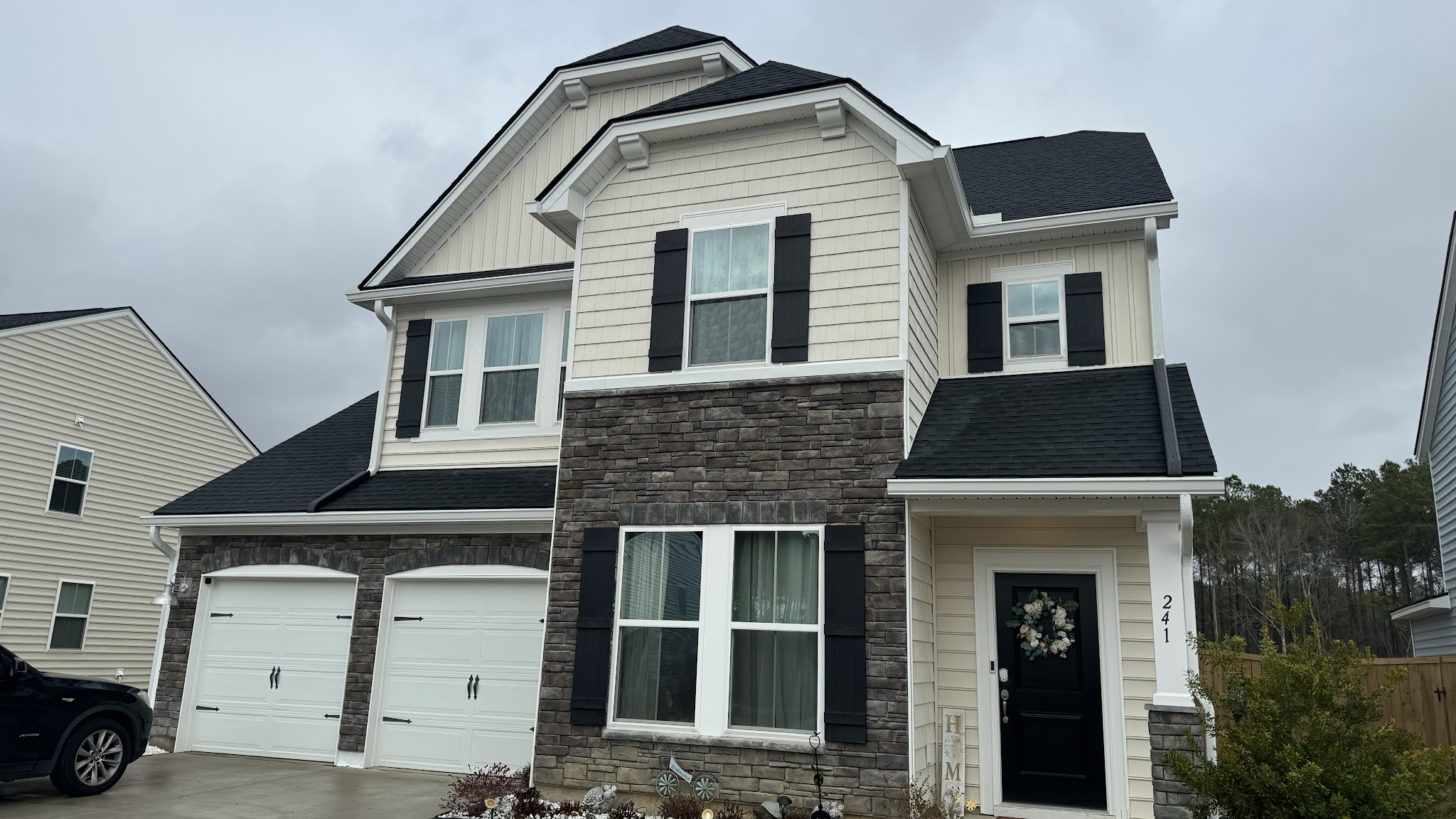 Stone and siding home with gutters along both roof levels